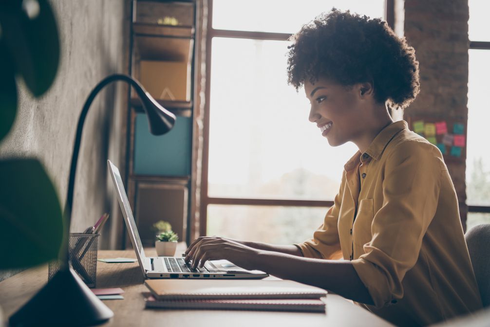 Profile side photo of black lady working on laptop at home office