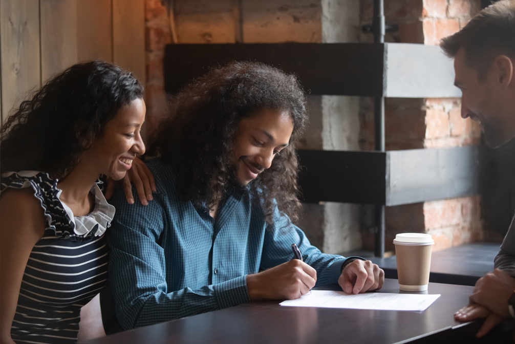 Multiracial couple signing agreement with listing agent