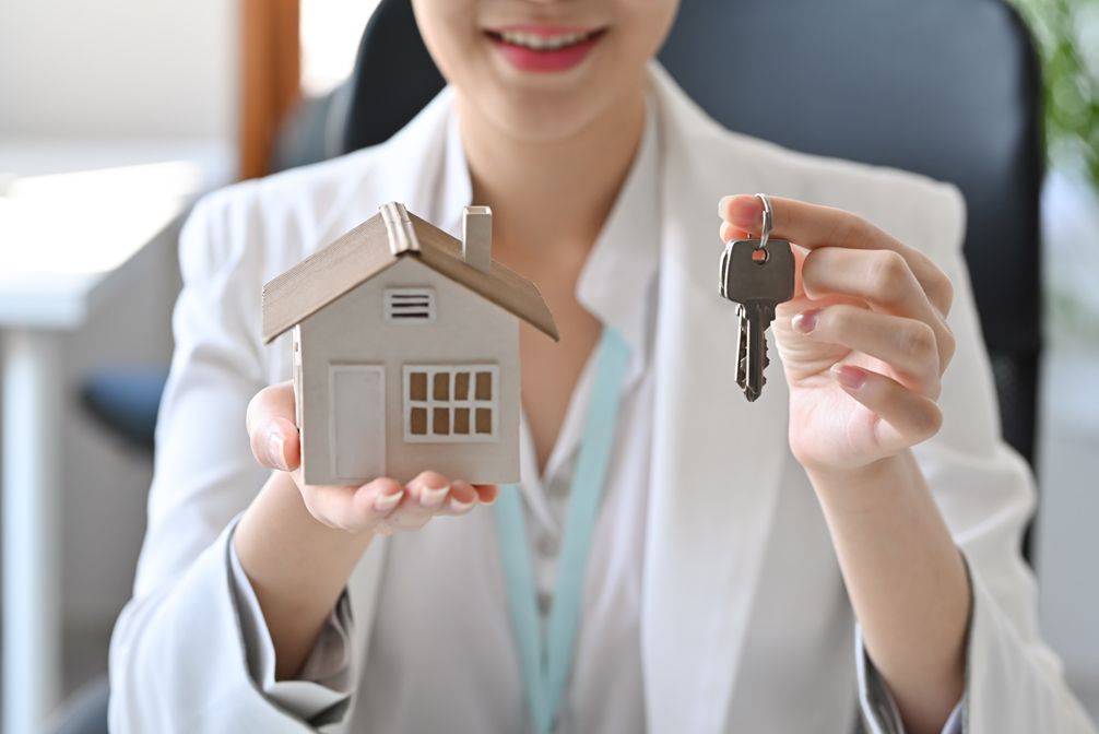 Real estate agent holding keys and model house